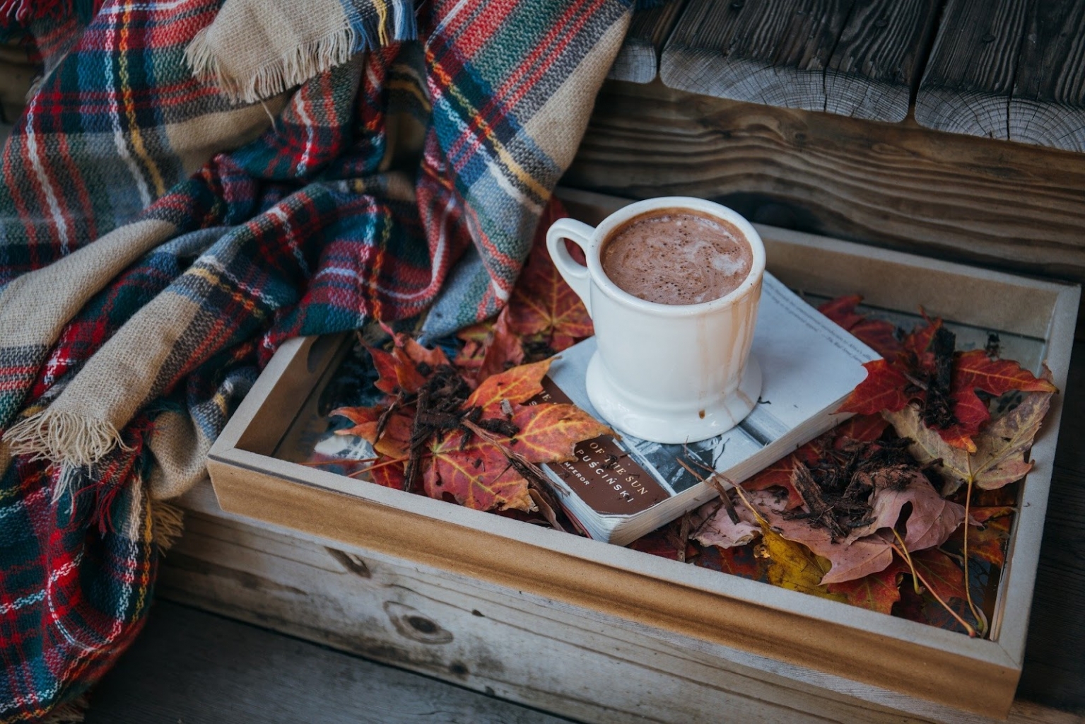 Forró csoki tálcán, mellette őszi falevelek és takaró