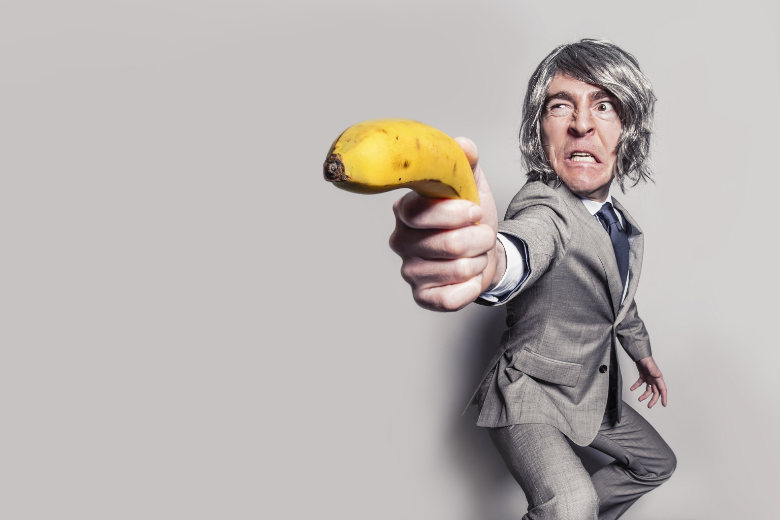 öltönyös férfi, aki egy banánt tart a kezében pisztolyként